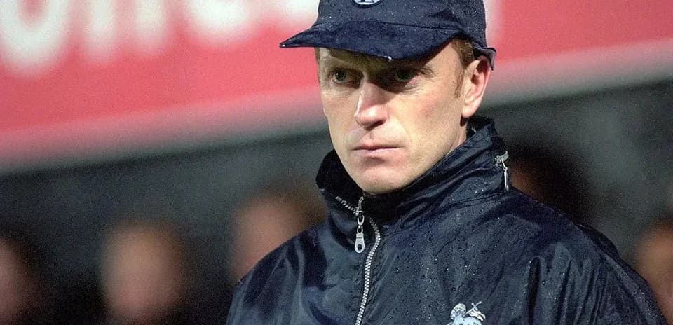 Coach in rain jacket at football match sidelines