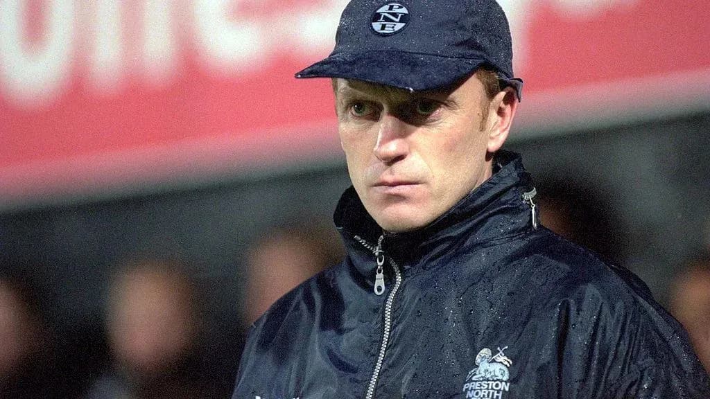 Coach in rain jacket at football match sidelines