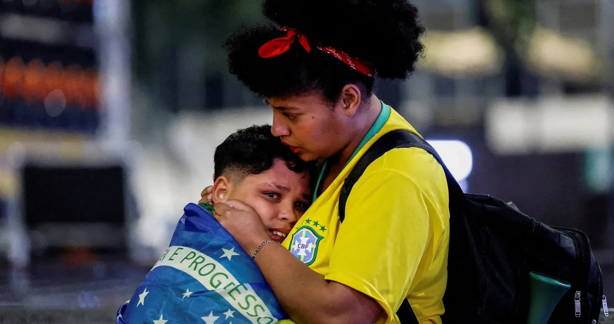 Woman comforting child wrapped in Brazilian flag