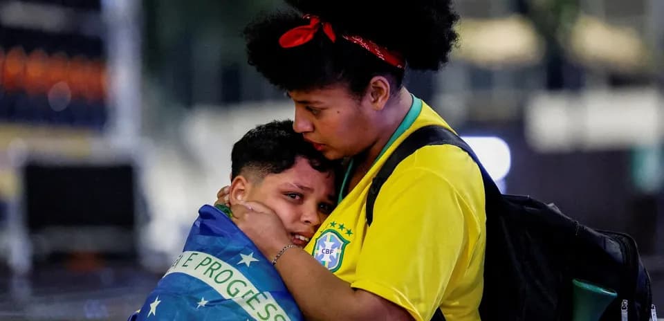 Woman comforting child wrapped in Brazilian flag