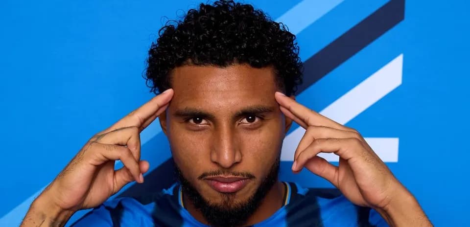 Player posing with fingers on temples against blue background