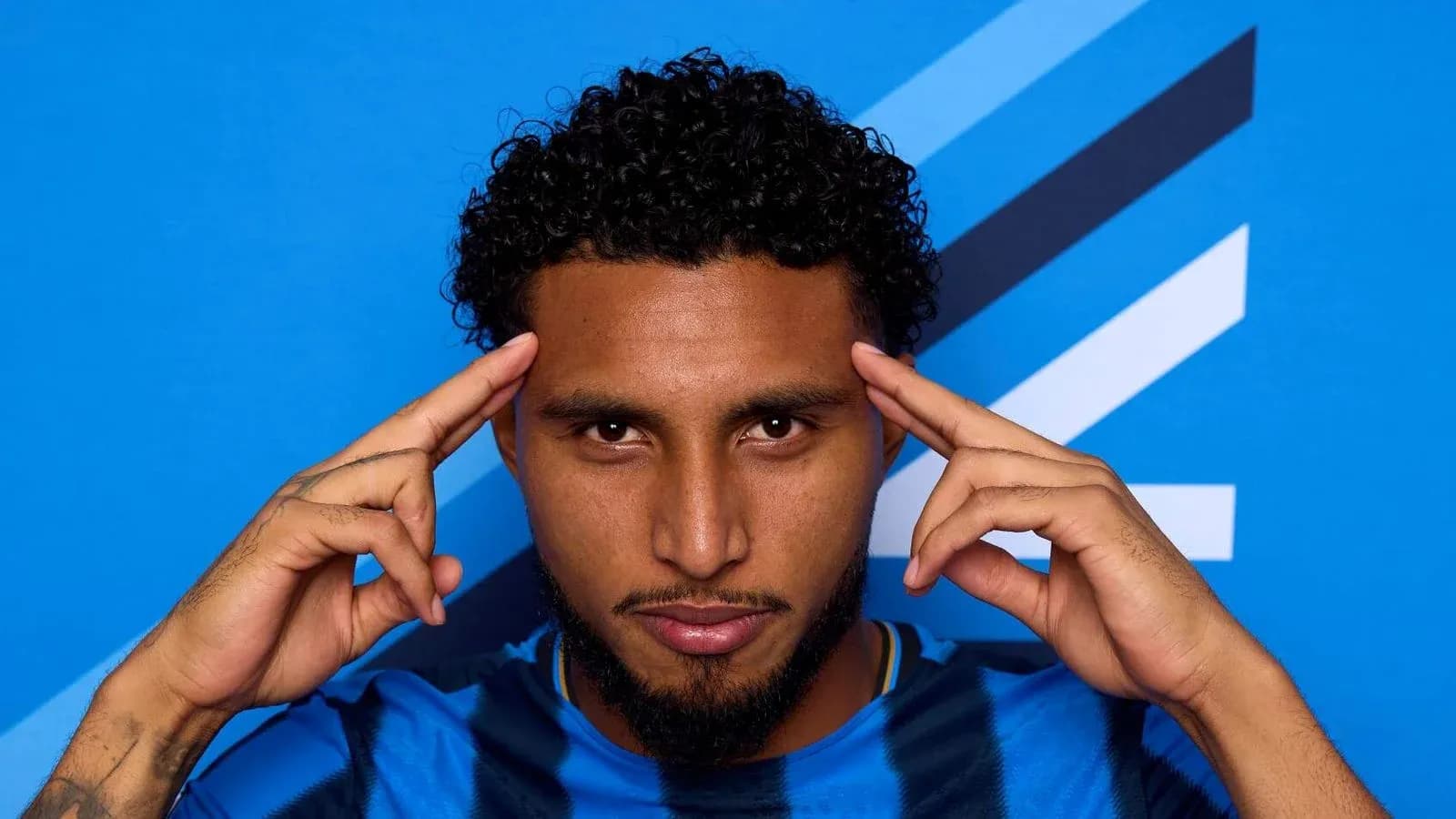 Player posing with fingers on temples against blue background