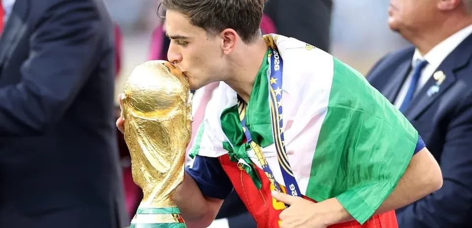 Player kissing World Cup trophy wearing national flag