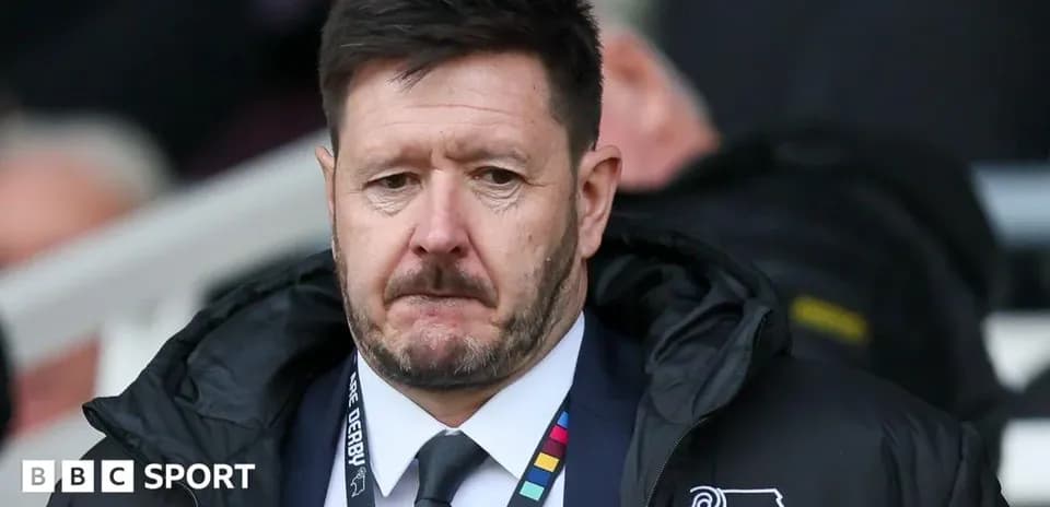 Manager in Derby County jacket on sidelines