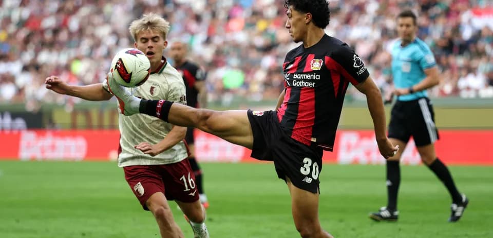 Player kicking ball while another player approaches