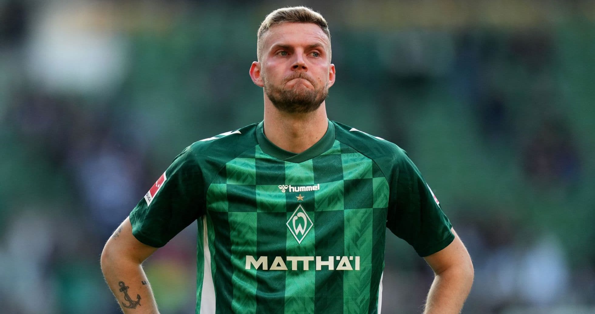 Player in green jersey looking concerned on the field