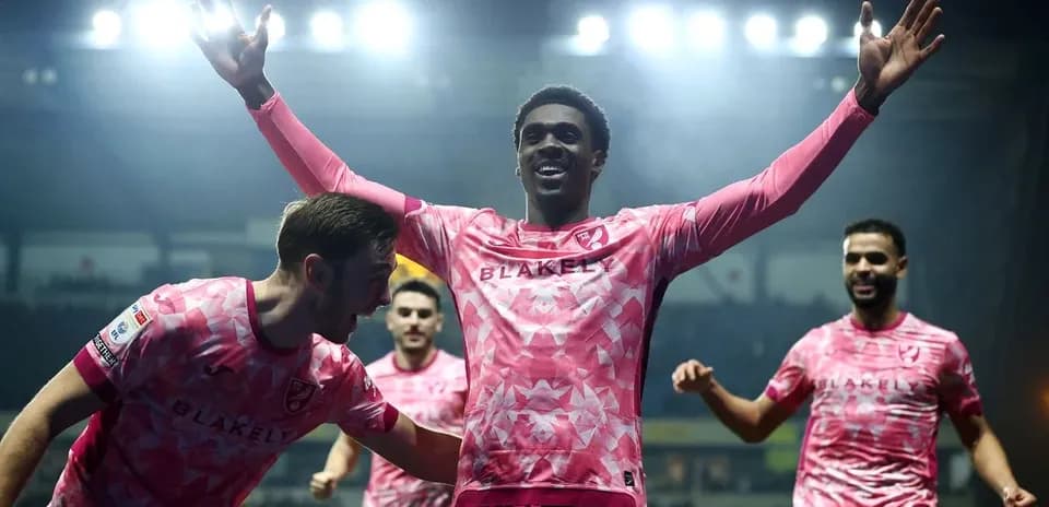 Players celebrating a goal in pink jerseys