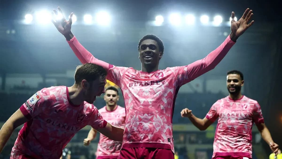 Players celebrating a goal in pink jerseys