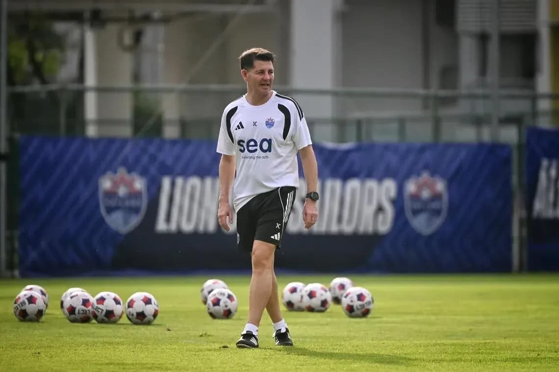 Coach walking on training pitch with soccer balls