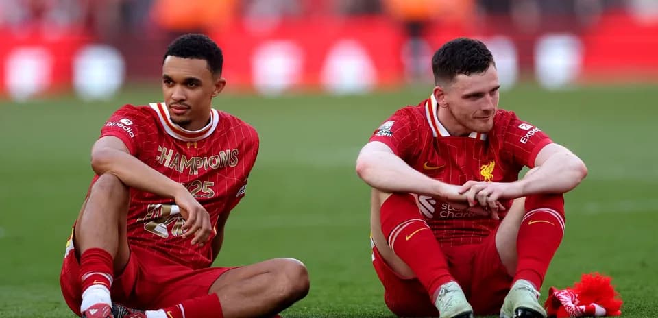 Two Liverpool players seated on the pitch post-match