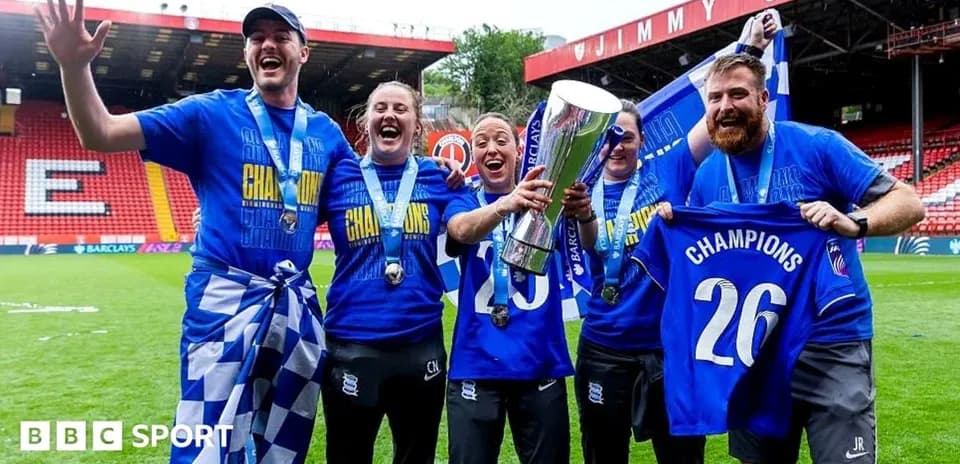 Team celebrating with trophy and banners on field