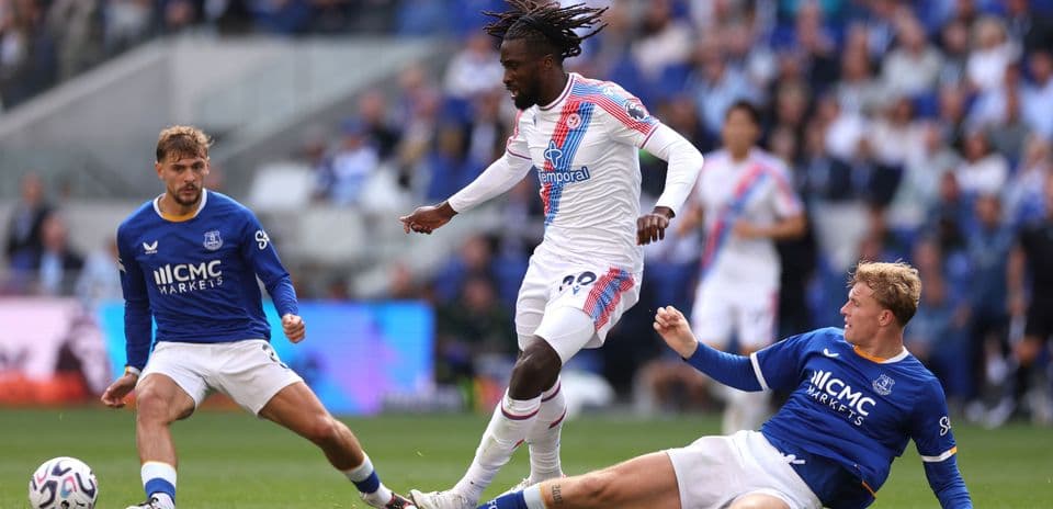 Player in white dribbling past two opponents in blue