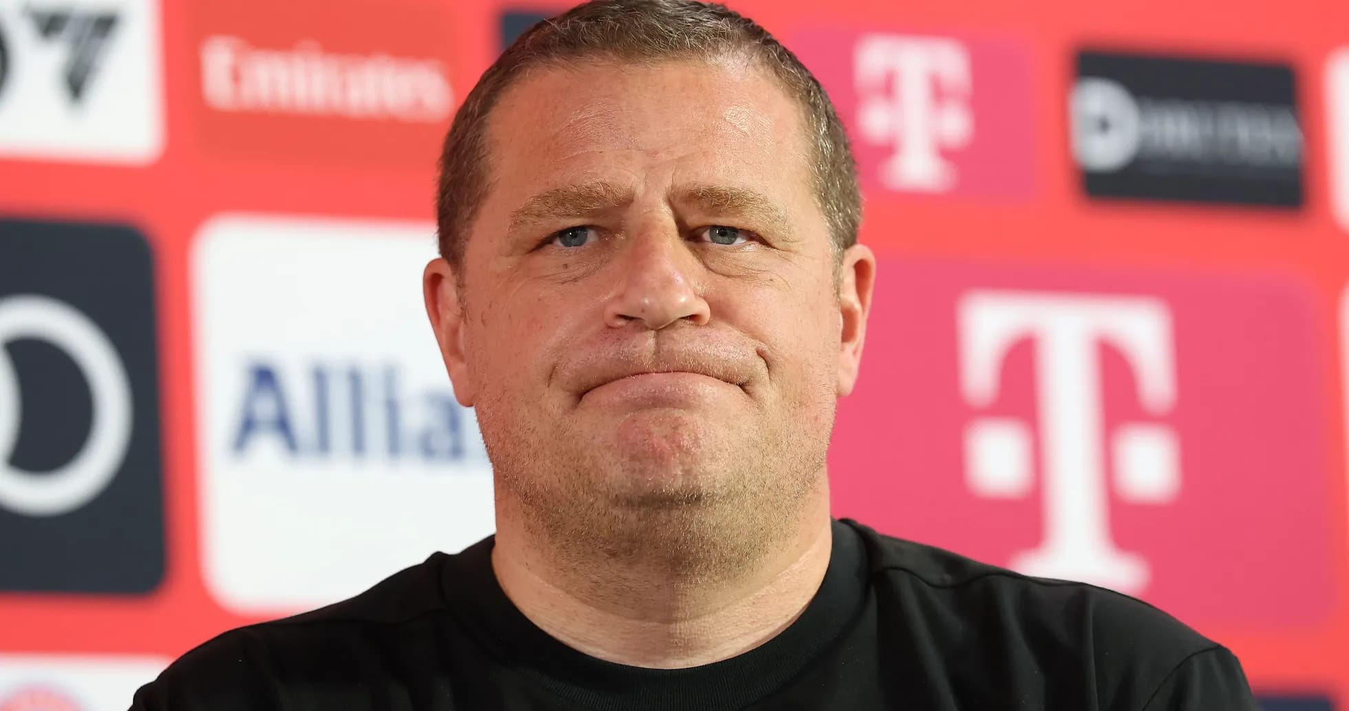 Manager at press conference with sponsor logos in background