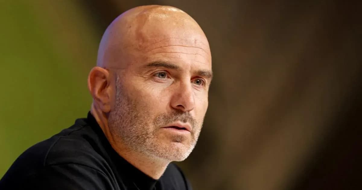 Man speaking at press conference with serious expression