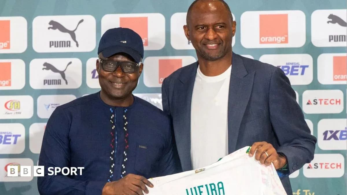 Two men holding a football jersey at a press event Two men holding a football jersey at a press event