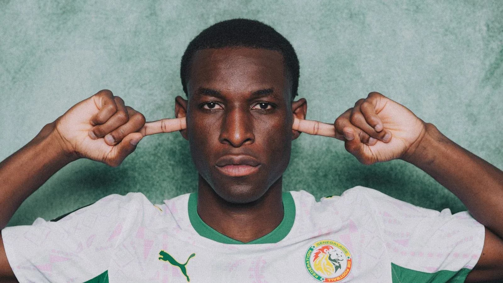 Player in Senegal jersey covering ears with fingers Player in Senegal jersey covering ears with fingers