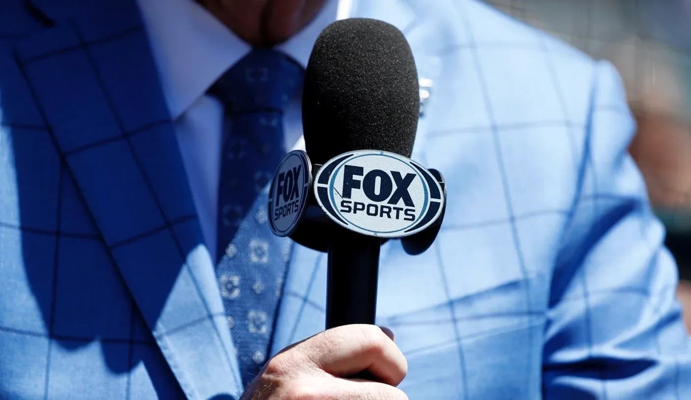 Person holding FOX Sports microphone in blue suit Person holding FOX Sports microphone in blue suit