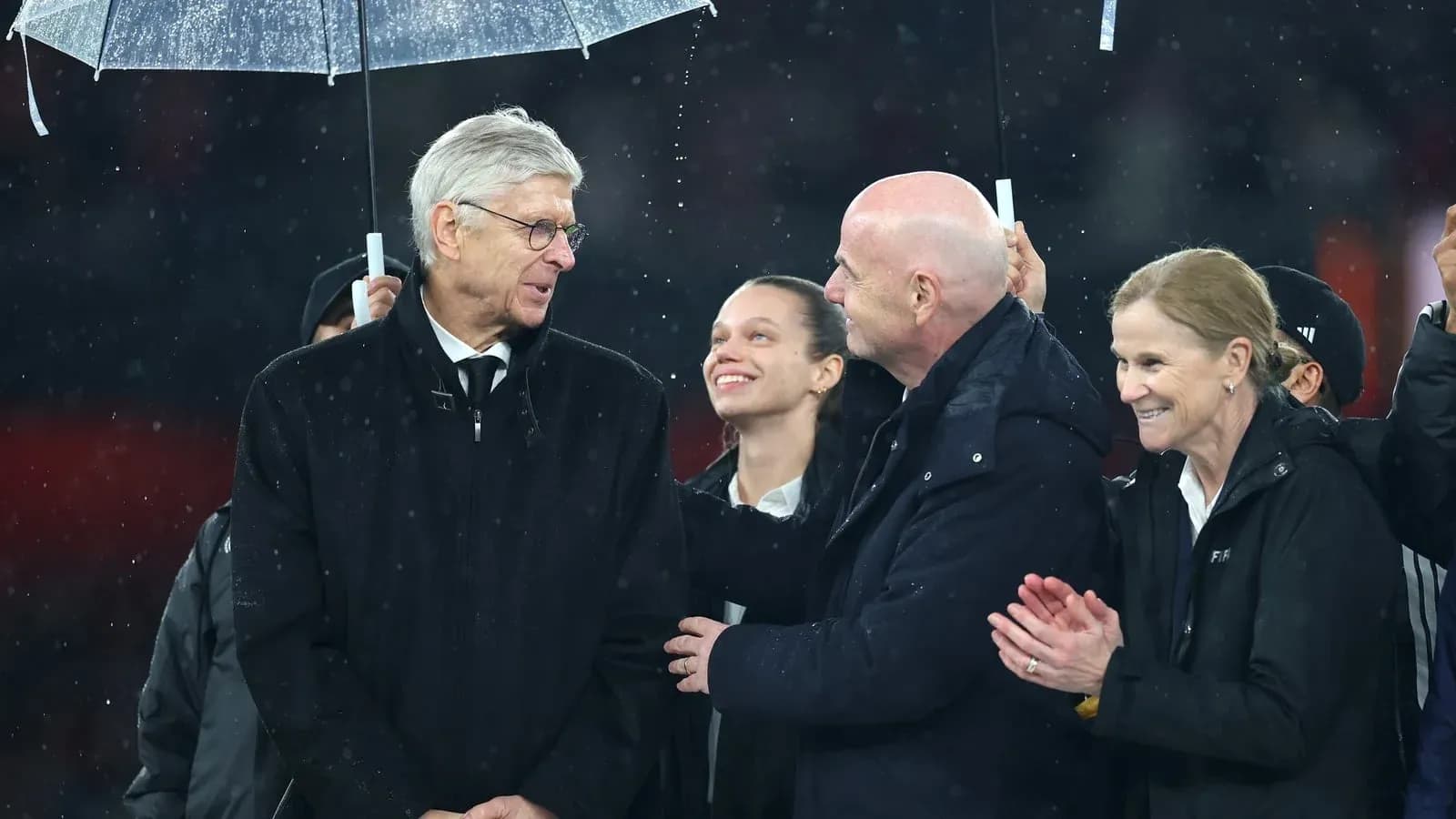 Group of people speaking under an umbrella in rain Group of people speaking under an umbrella in rain