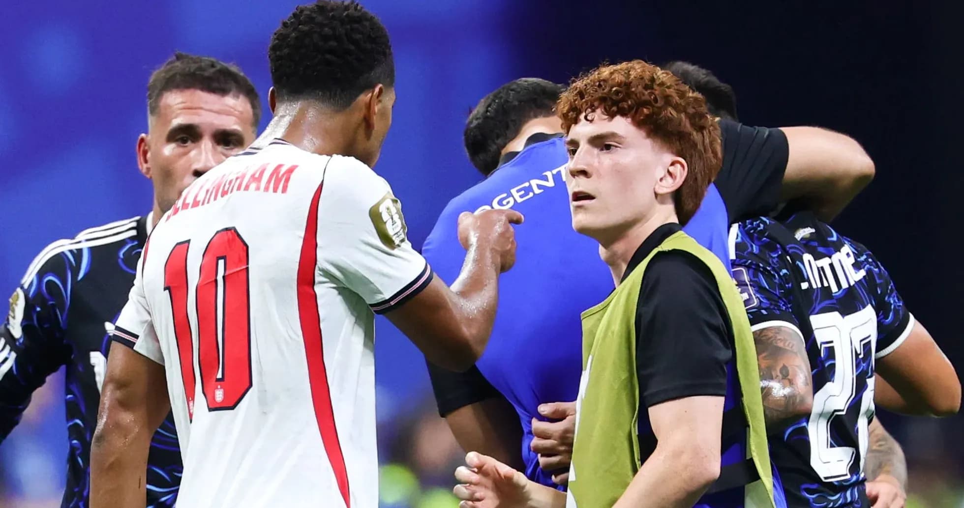 Players interacting during a match, with one in green vest Players interacting during a match, with one in green vest