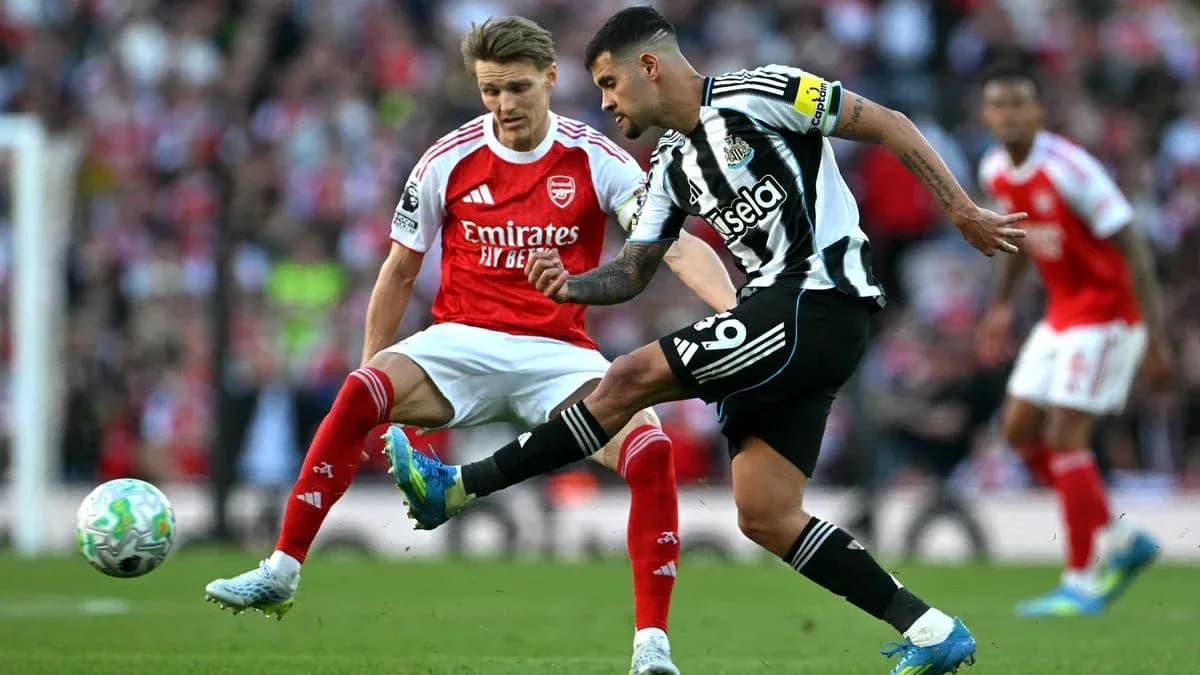 Newcastle player kicking ball past Arsenal opponent Newcastle player kicking ball past Arsenal opponent