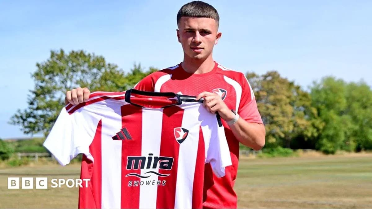 Player holding Cheltenham Town jersey during announcement Player holding Cheltenham Town jersey during announcement