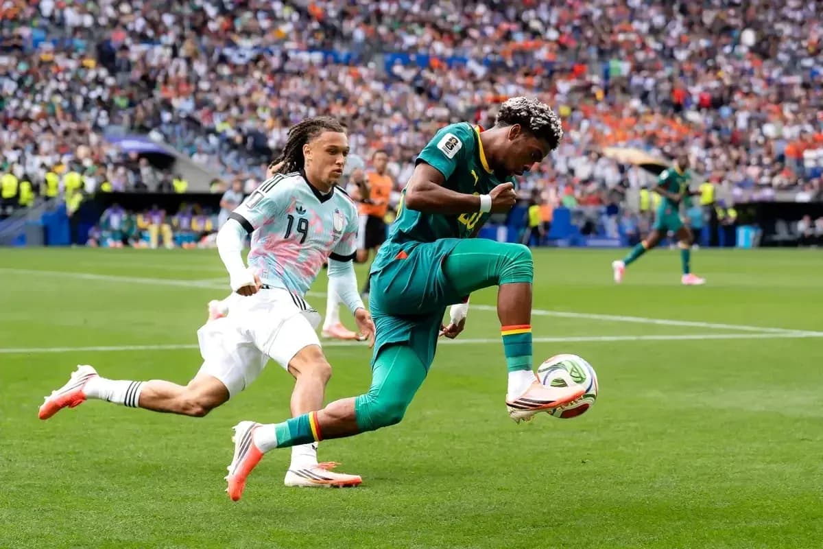 Player kicking ball while being chased by opponent Player kicking ball while being chased by opponent