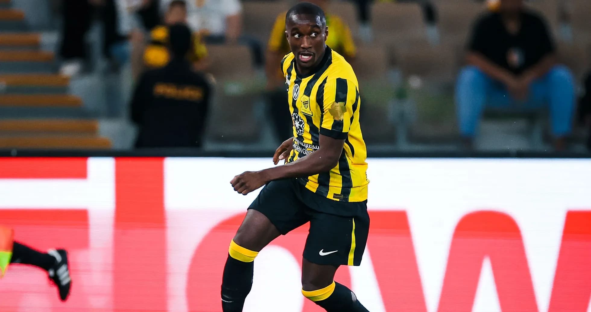 Player in yellow and black kit running with ball Player in yellow and black kit running with ball