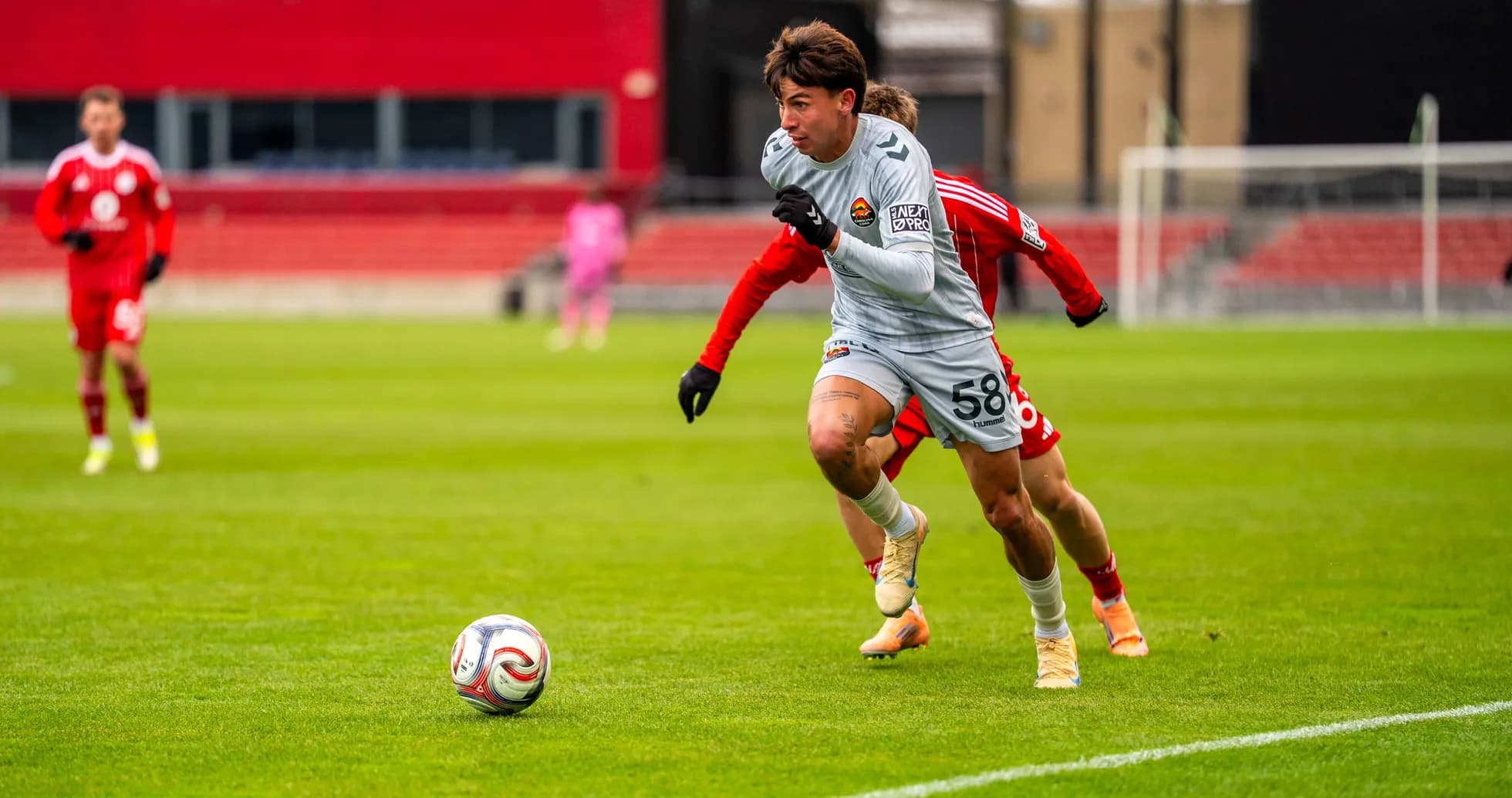 Player in gray chasing the ball on field Player in gray chasing the ball on field