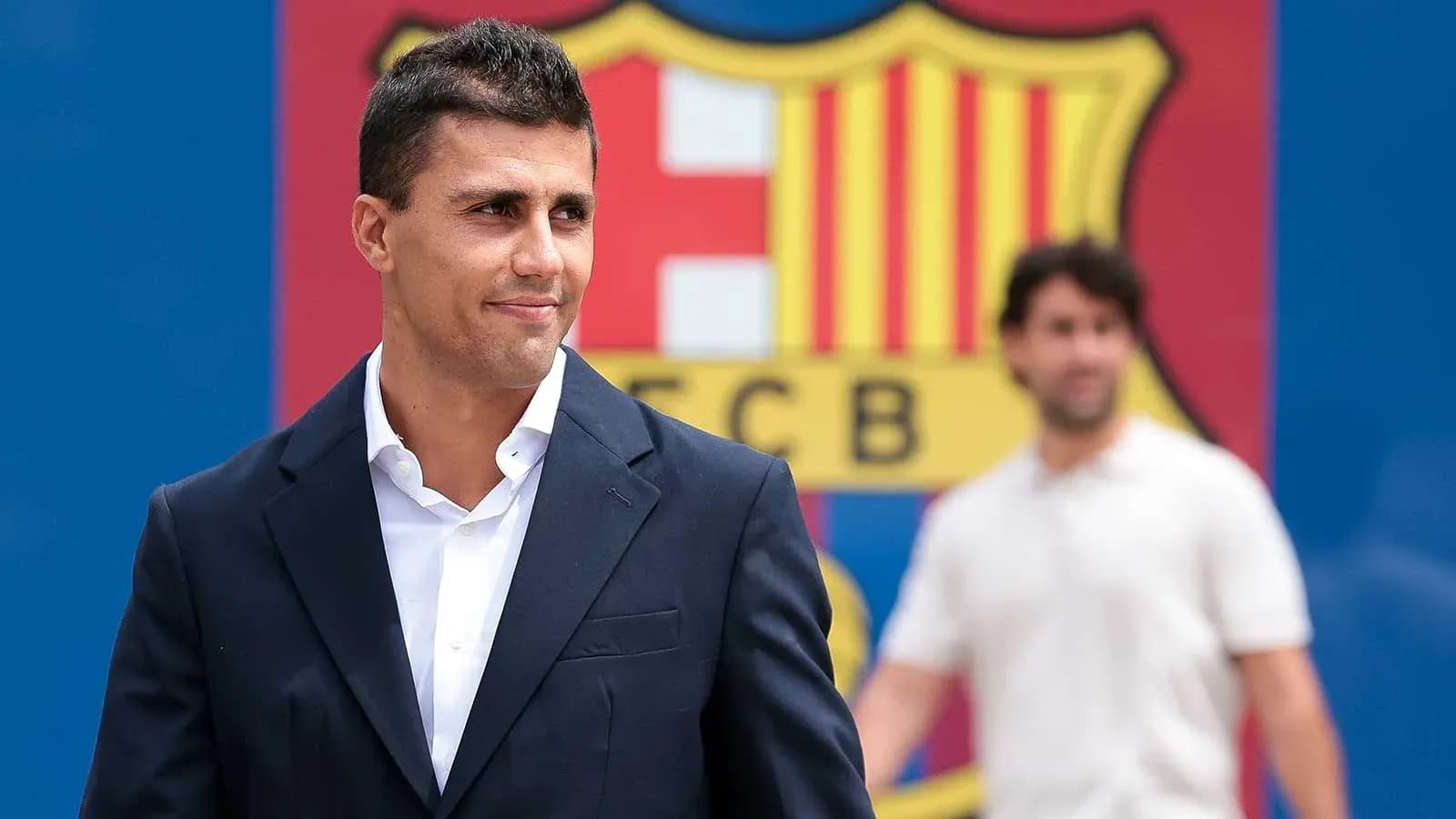 Man in suit standing in front of FC Barcelona logo Man in suit standing in front of FC Barcelona logo