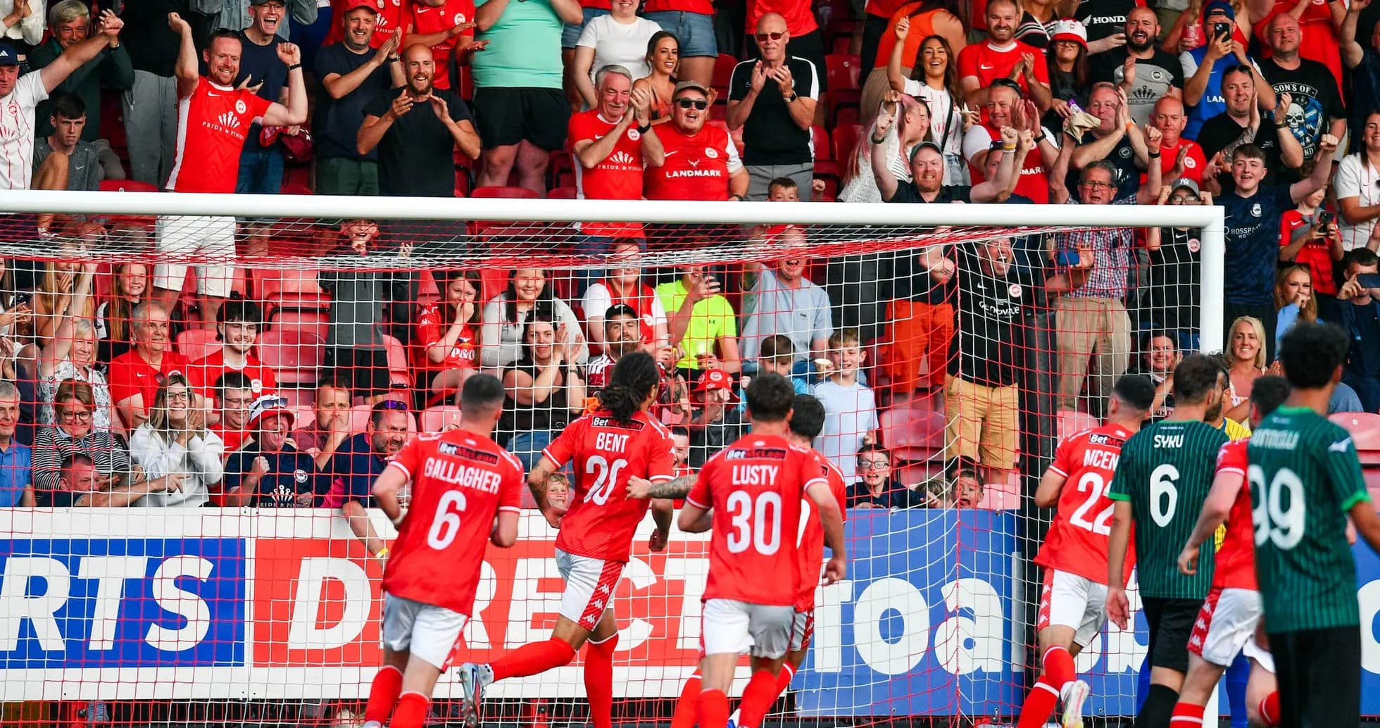 Players celebrating goal with cheering fans Players celebrating goal with cheering fans