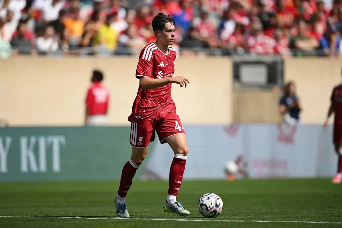 Player in red Liverpool kit dribbling ball on field Player in red Liverpool kit dribbling ball on field
