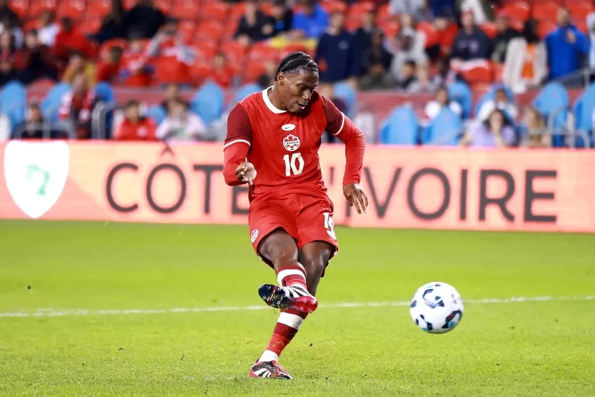 Player kicking a soccer ball in red uniform Player kicking a soccer ball in red uniform