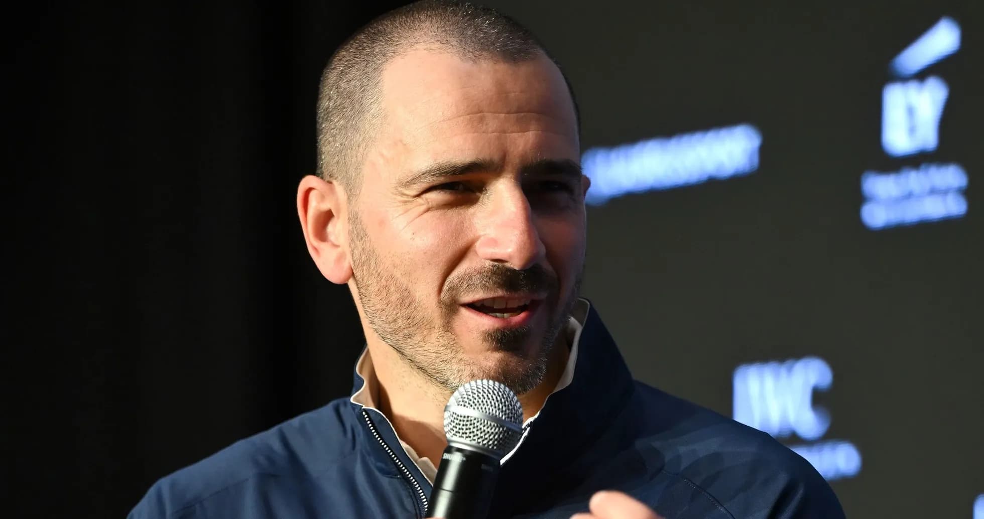 Man speaking into a microphone at event Man speaking into a microphone at event