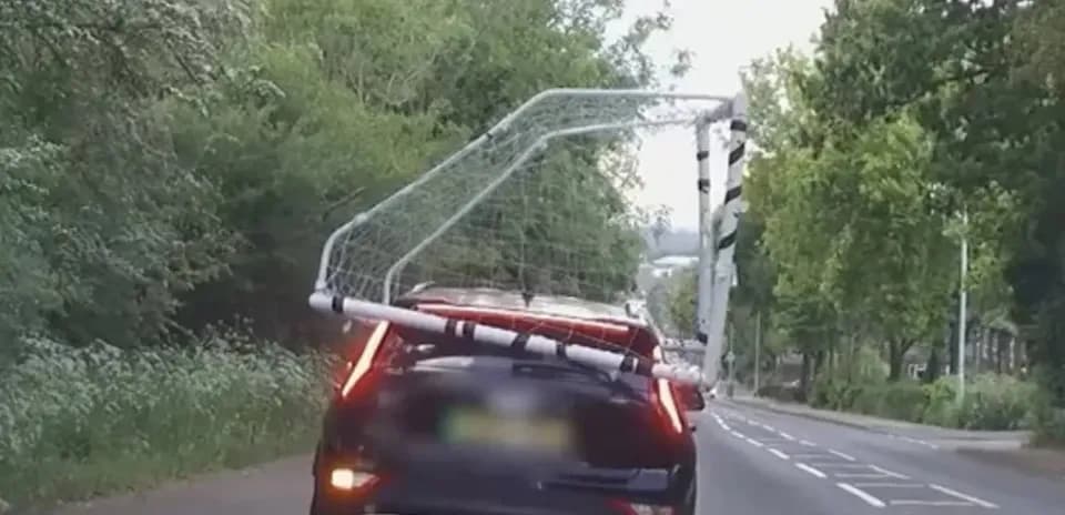 Car transporting a football goal on the road Car transporting a football goal on the road