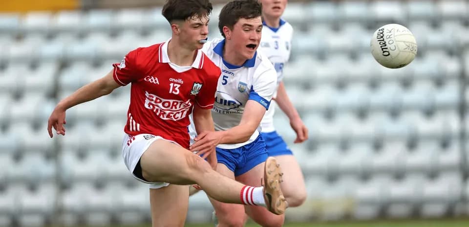 Player kicking a ball while being challenged by opponent Player kicking a ball while being challenged by opponent