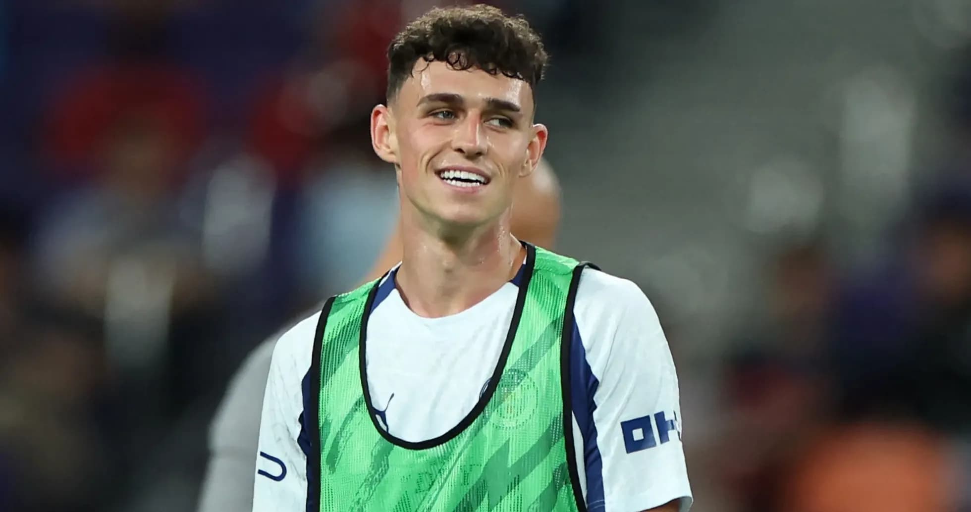 Player smiling in training vest on pitch Player smiling in training vest on pitch