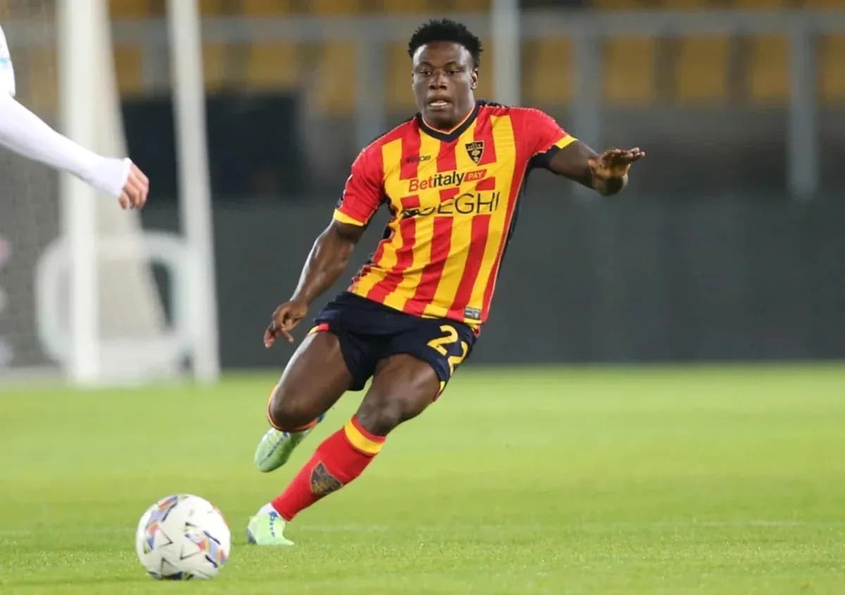 Player in yellow and red kit dribbling ball on field Player in yellow and red kit dribbling ball on field