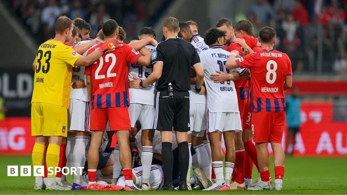 Players from both teams huddled around an injured player Players from both teams huddled around an injured player