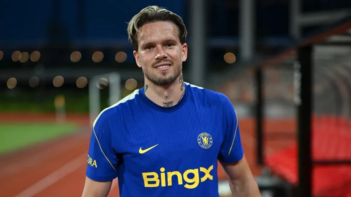 Player in blue Chelsea jersey smiling on pitch Player in blue Chelsea jersey smiling on pitch
