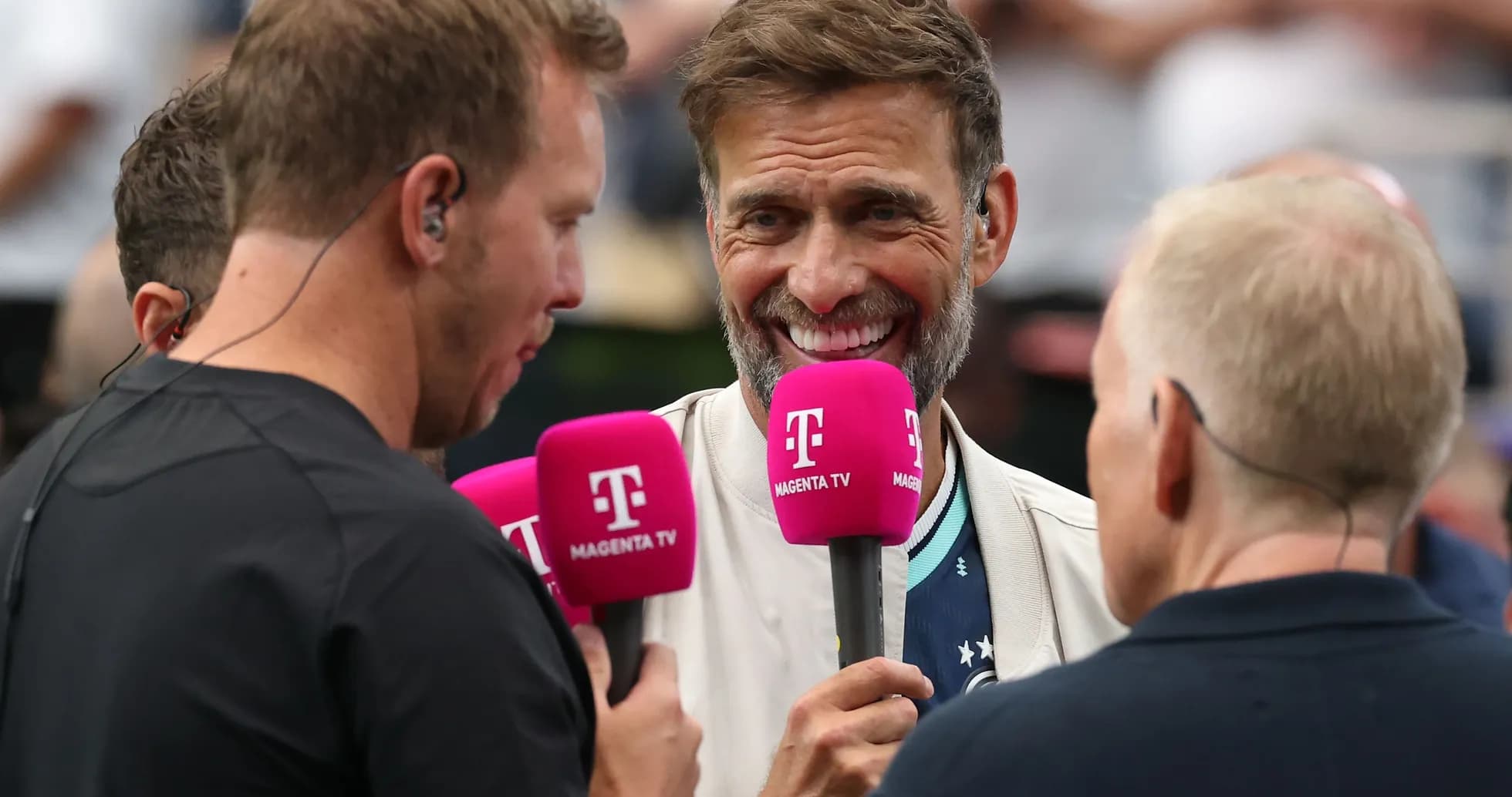 Four commentators discussing with microphones at event Four commentators discussing with microphones at event