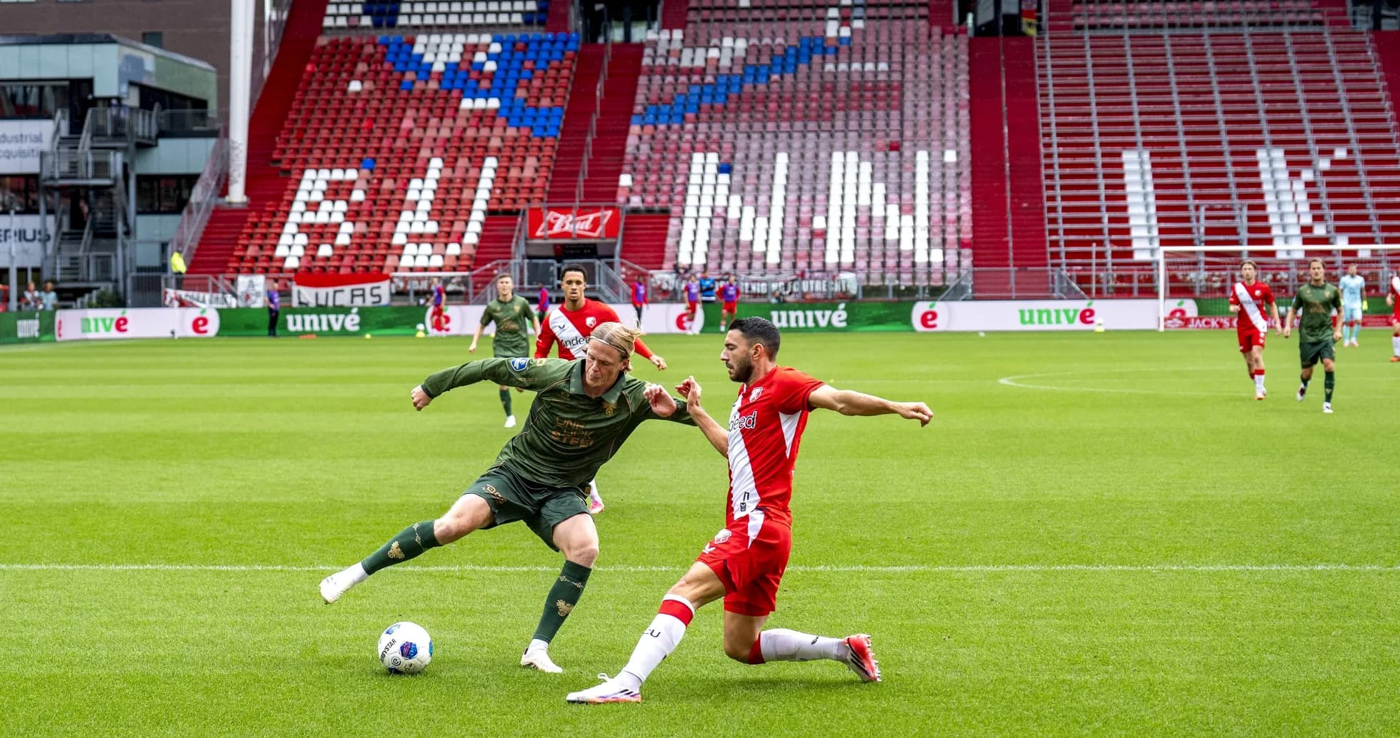 Two players battling for the ball on the pitch Two players battling for the ball on the pitch