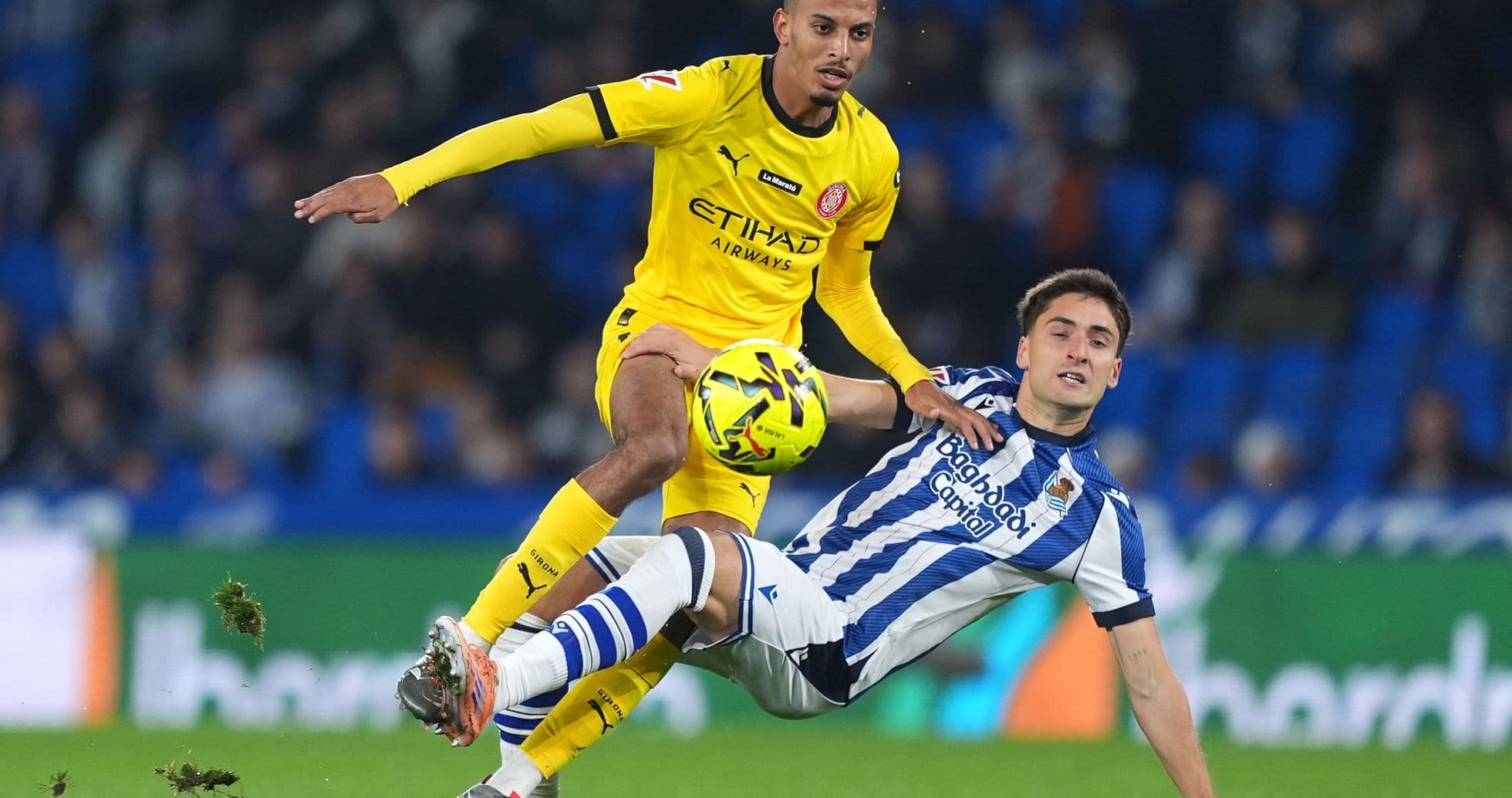 Girona player tackling Real Sociedad opponent Girona player tackling Real Sociedad opponent