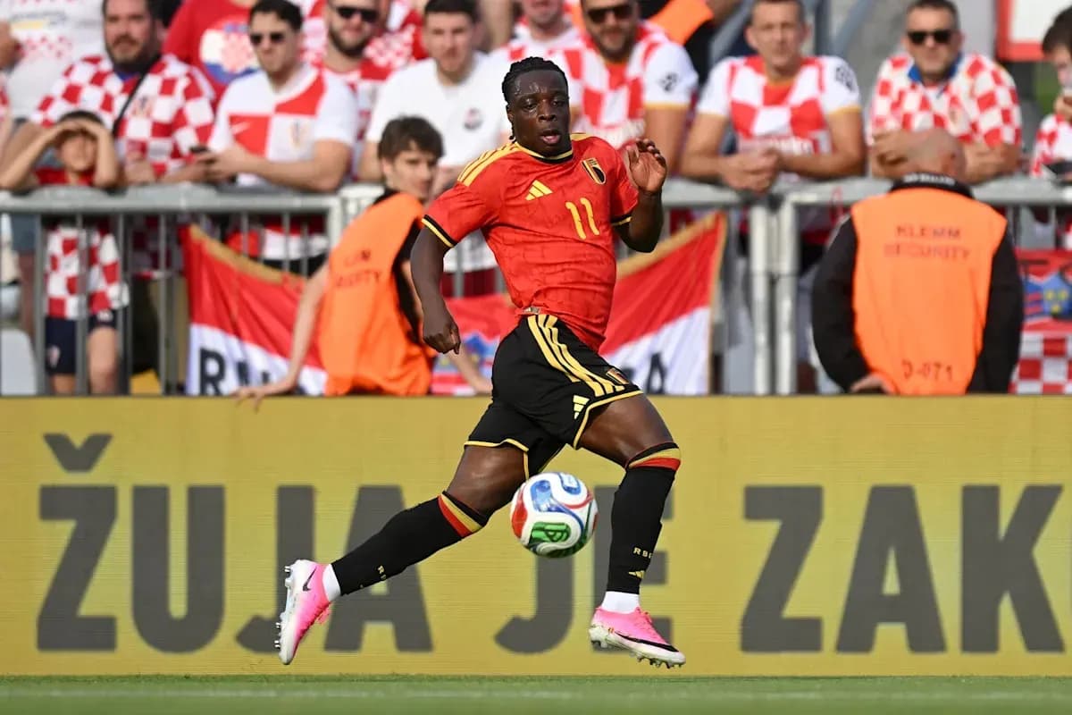 Belgian player dribbling the ball past fans Belgian player dribbling the ball past fans