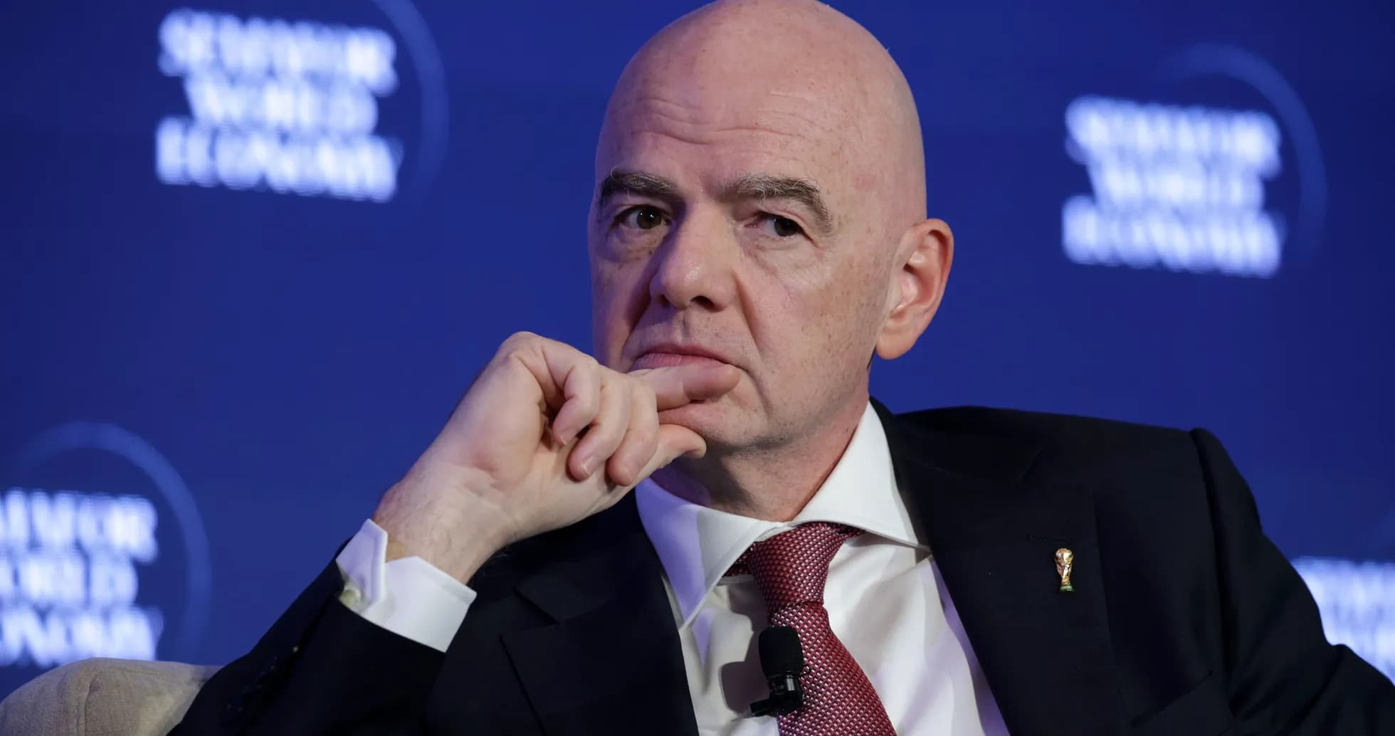 Man in suit speaking at conference with FIFA emblem Man in suit speaking at conference with FIFA emblem