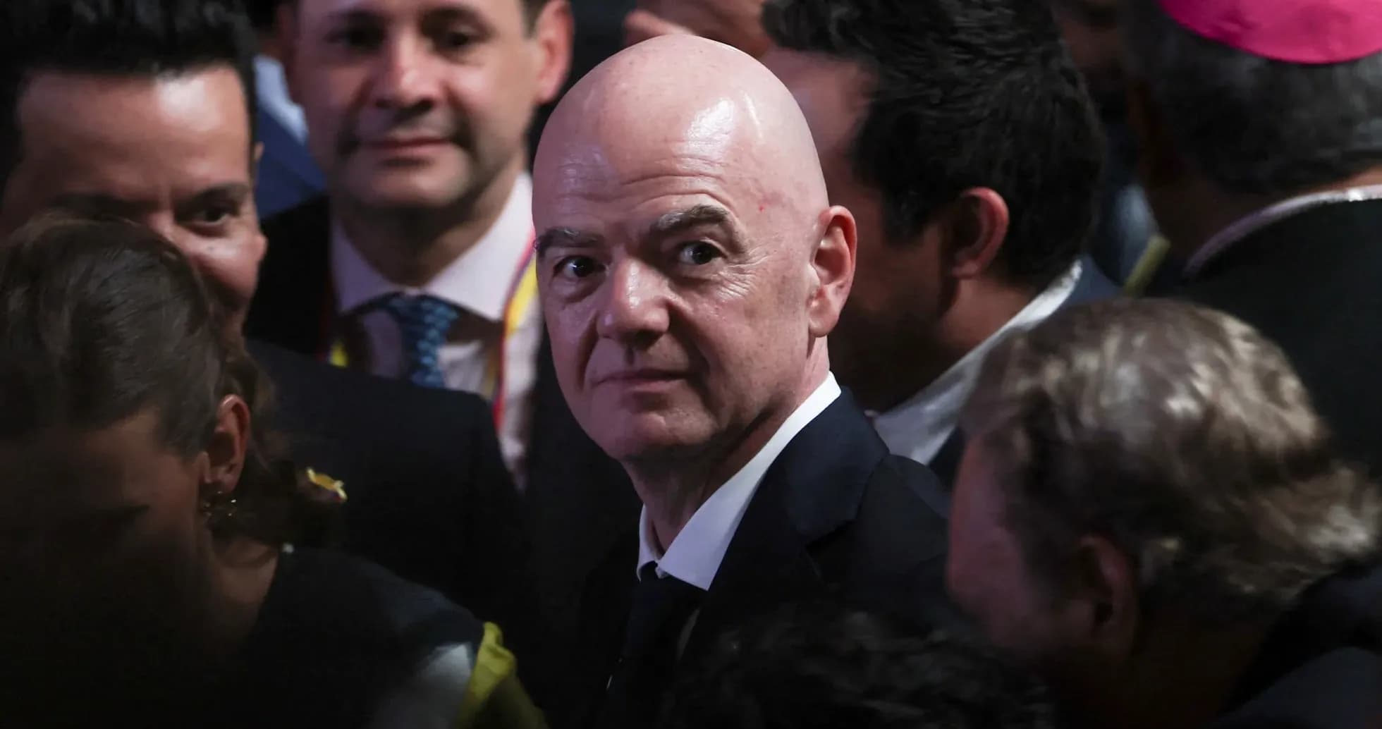 Man in suit surrounded by crowd at event Man in suit surrounded by crowd at event