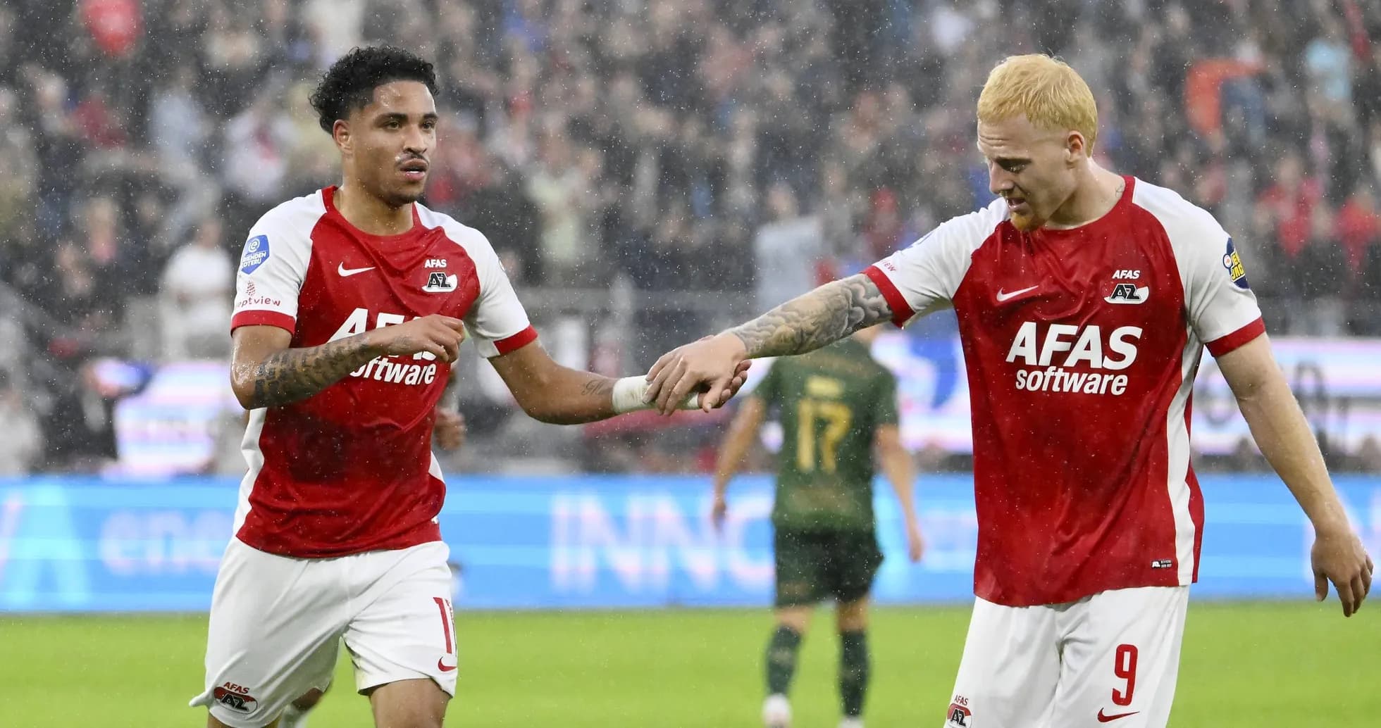 Two AZ Alkmaar players celebrating on rainy pitch Two AZ Alkmaar players celebrating on rainy pitch