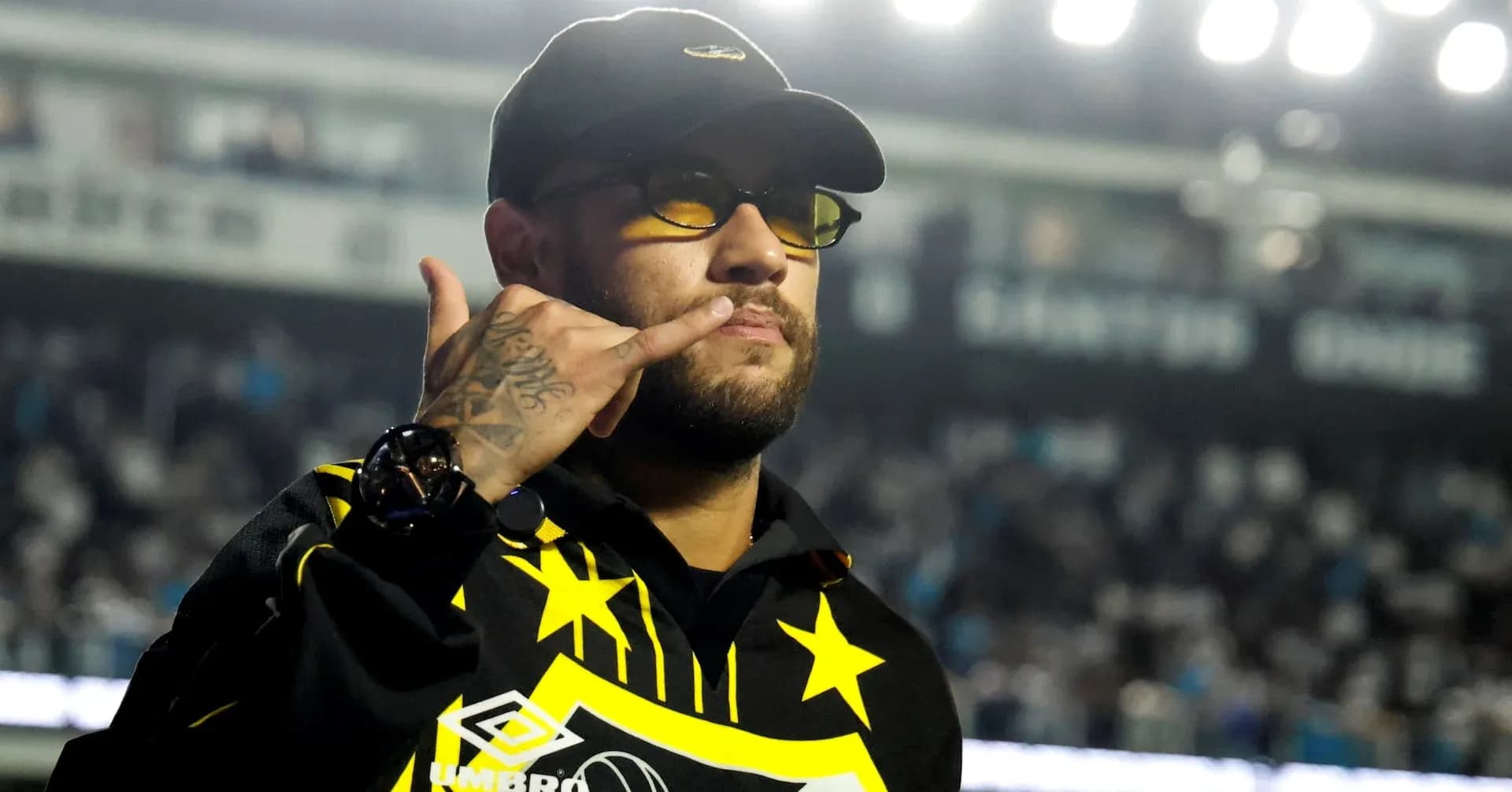 Man making phone gesture in sports venue Man making phone gesture in sports venue