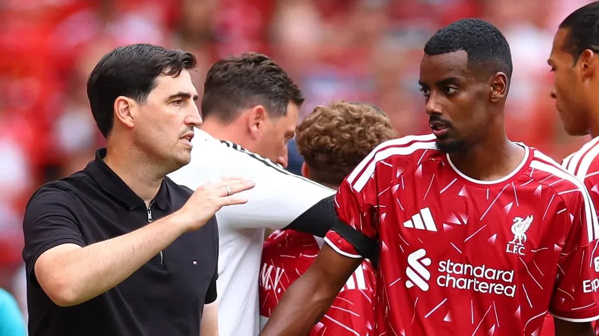 Coach discussing strategy with Liverpool player on field Coach discussing strategy with Liverpool player on field