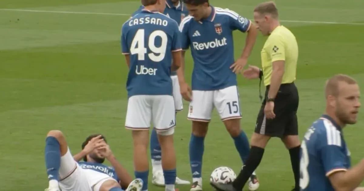 Player lying on field with teammates and referee nearby Player lying on field with teammates and referee nearby