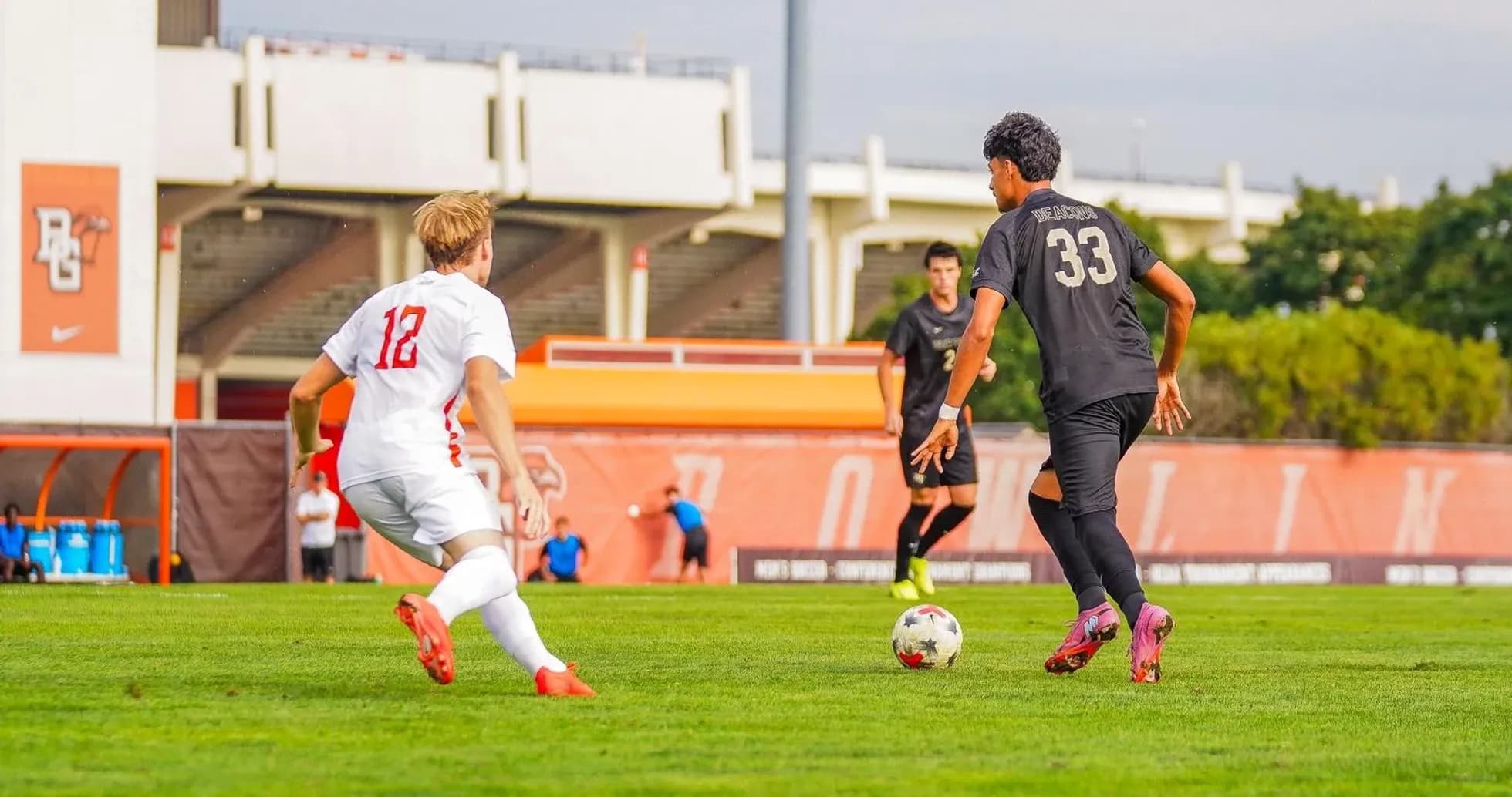 Player in white jersey chasing ball near opponent Player in white jersey chasing ball near opponent